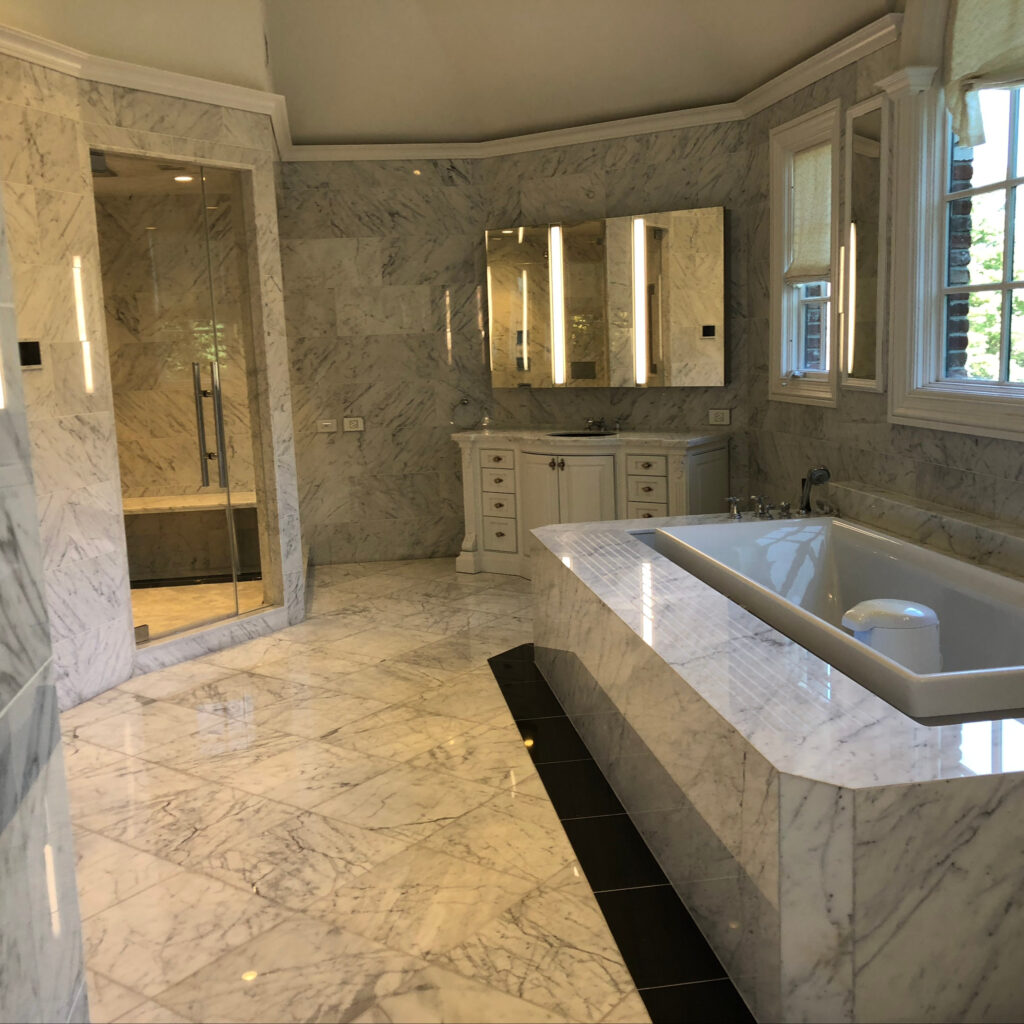 A recently built, cleaned, and polished grey marble bathroom, shower, and bath tub.
